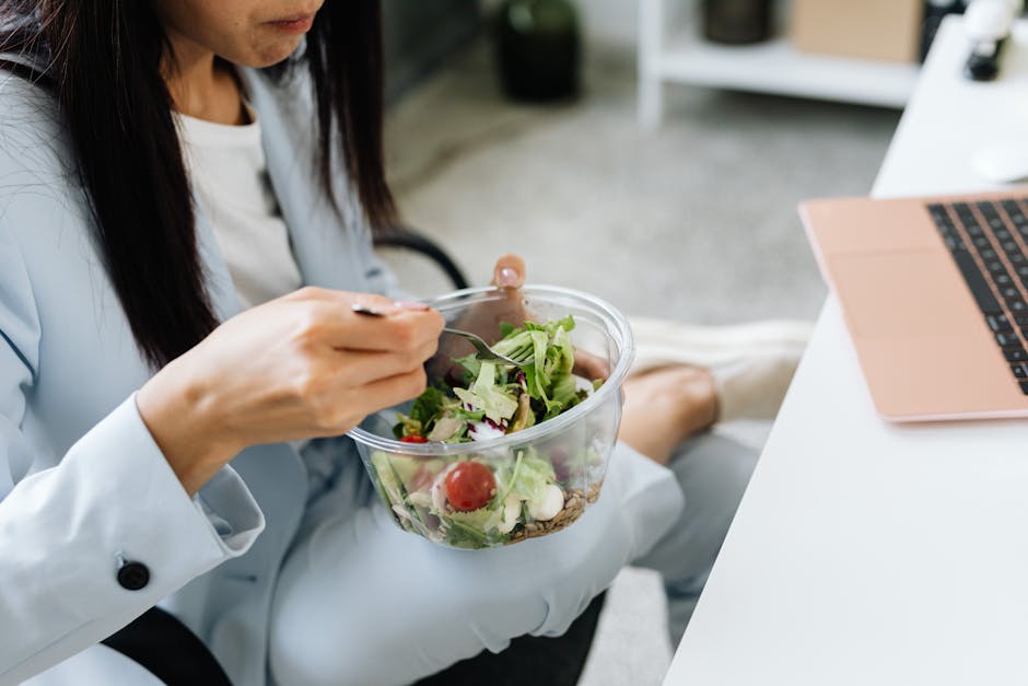Student eating a fresh salad at her desk next to her laptop between study sessions
