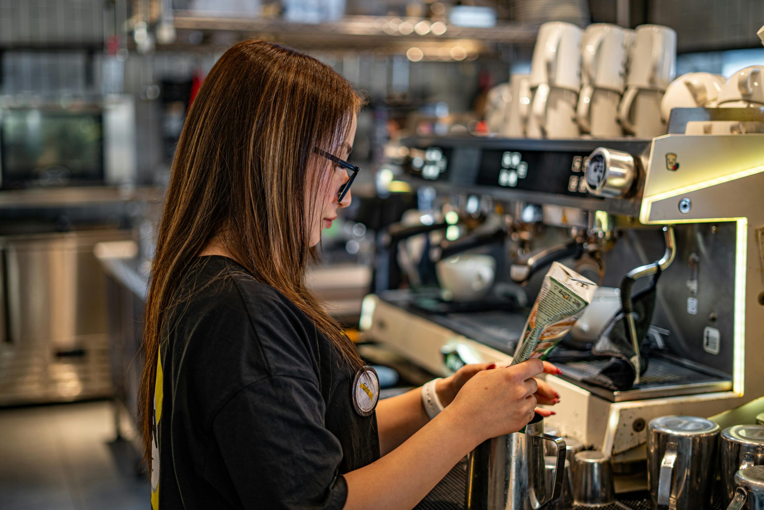 Young barista pulling shots at an espresso machine in a UK coffee shop