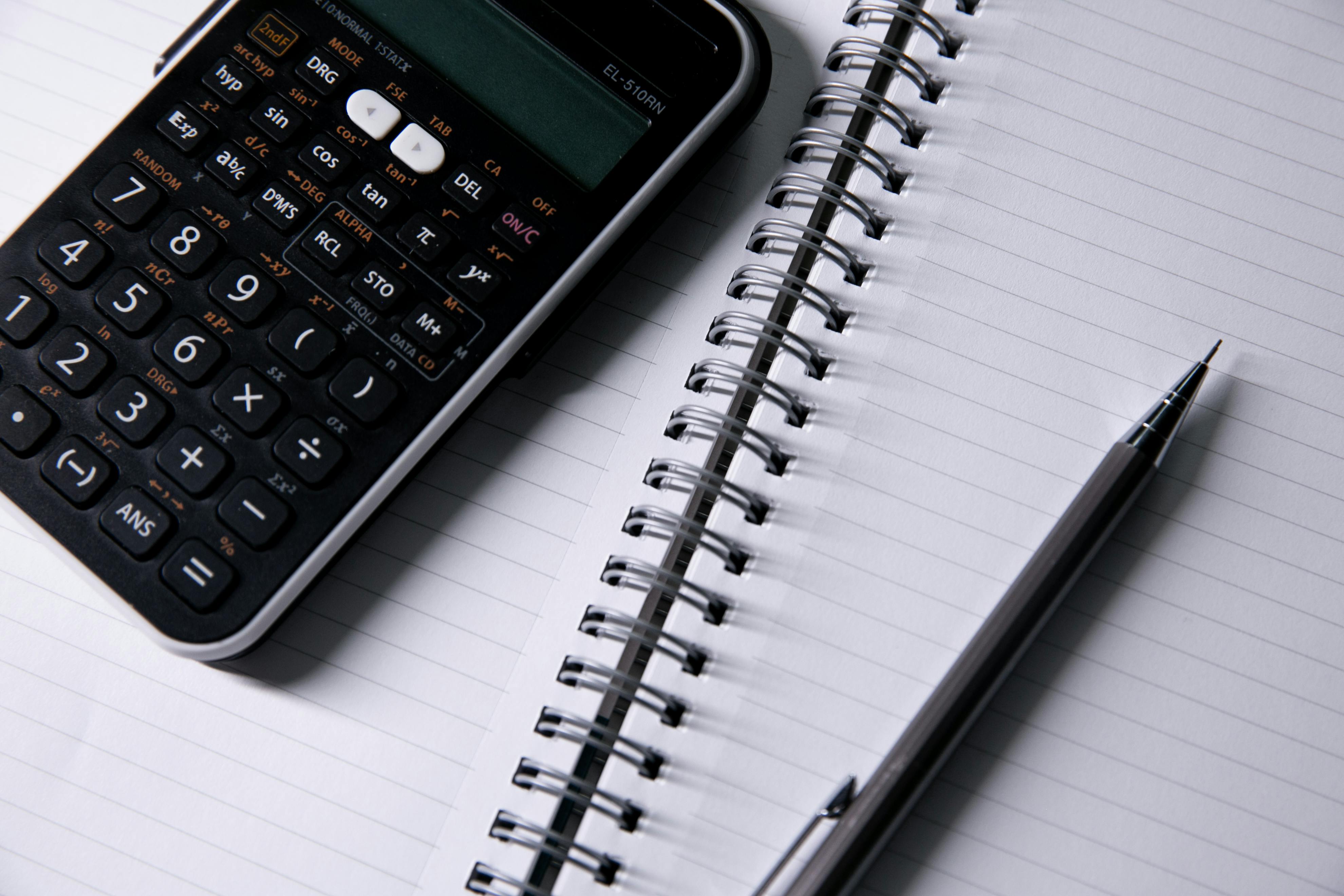 Cash, calculator and notebook next to a student budget template printout