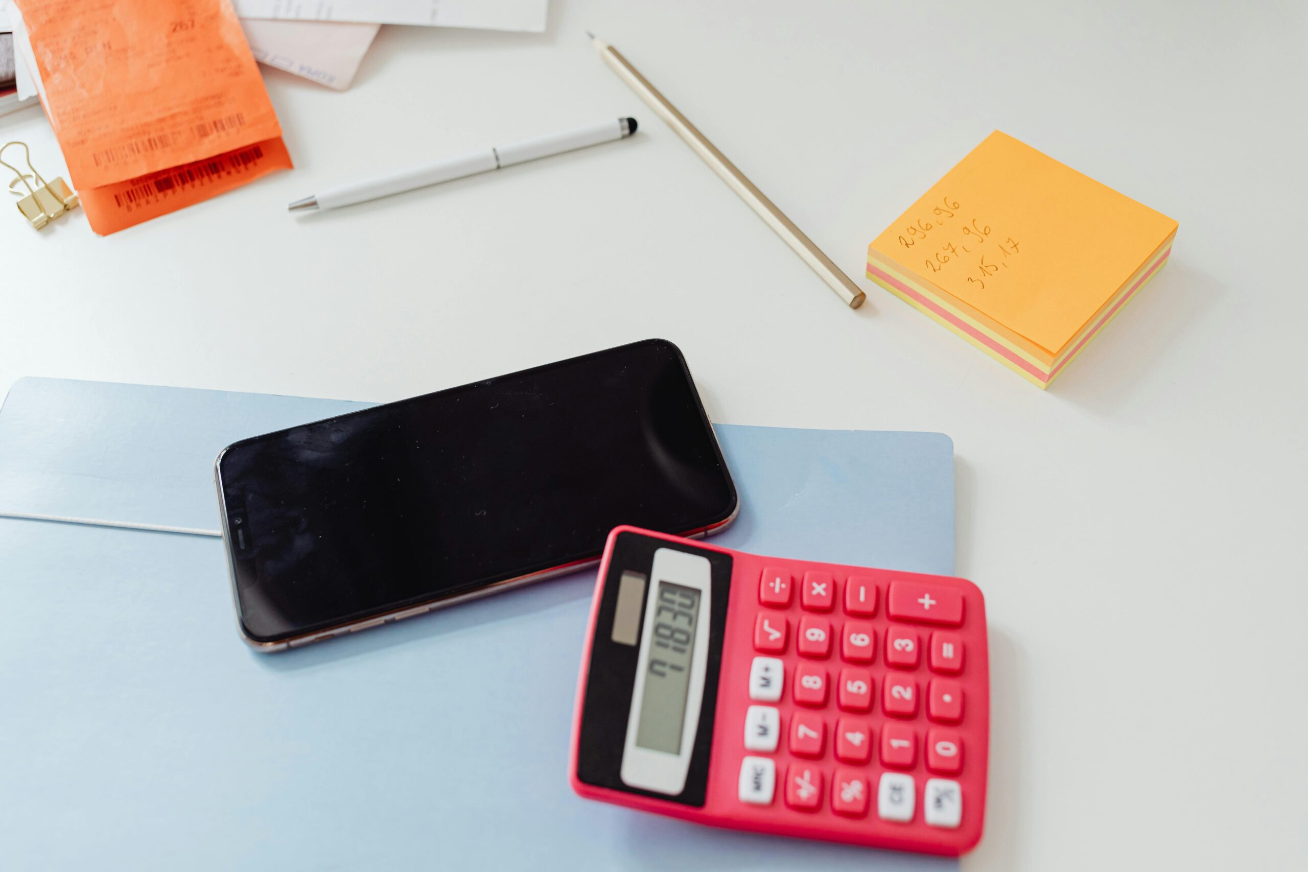 Person calculating net salary with a calculator and notepad
