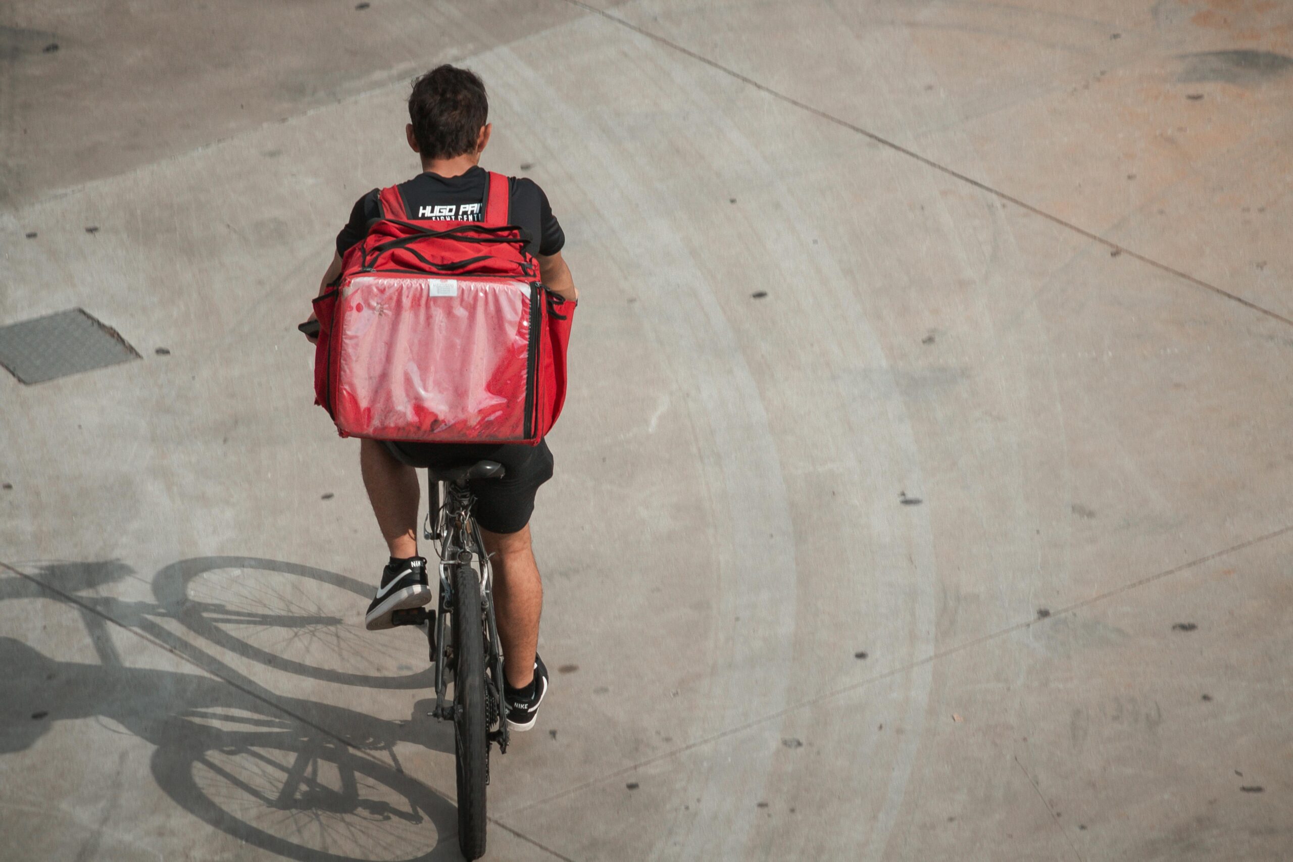 Food delivery cyclist with insulated backpack riding through a UK city