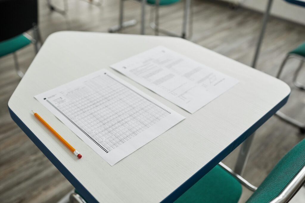 A-level maths exam paper, pencil and clock on a desk