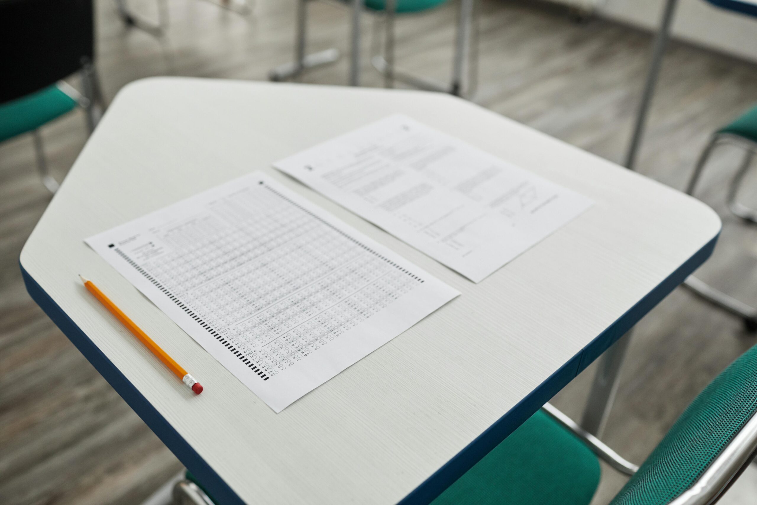 A-level maths exam paper, pencil and clock on a desk