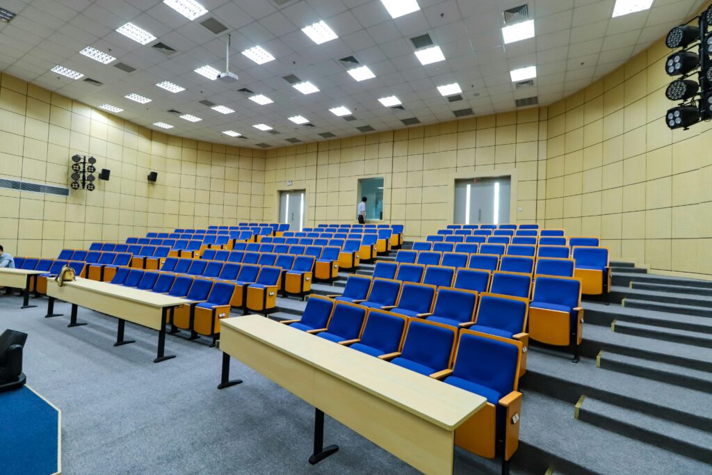 Spacious lecture hall with blue seats and desks ready for students.