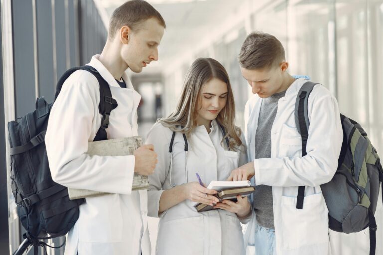 Three medical students in a hallway going through notes