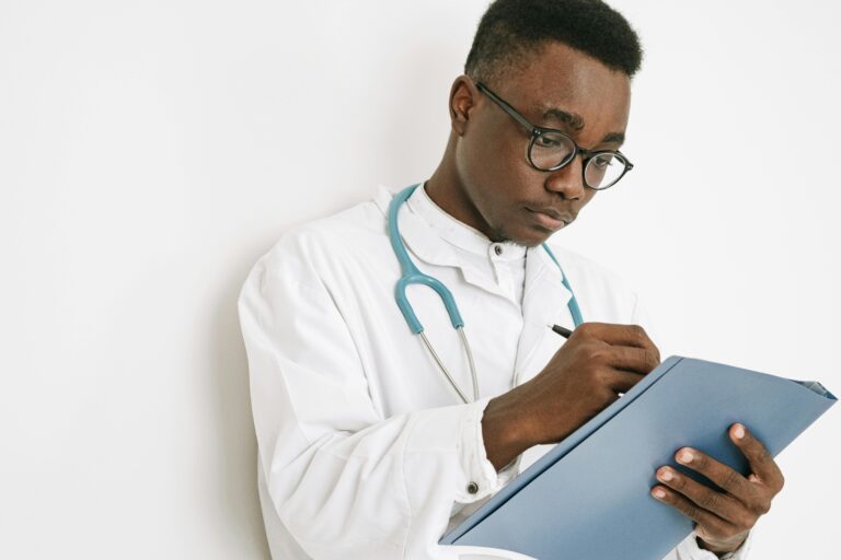 A doctor with a stethoscope writing on a clipboard