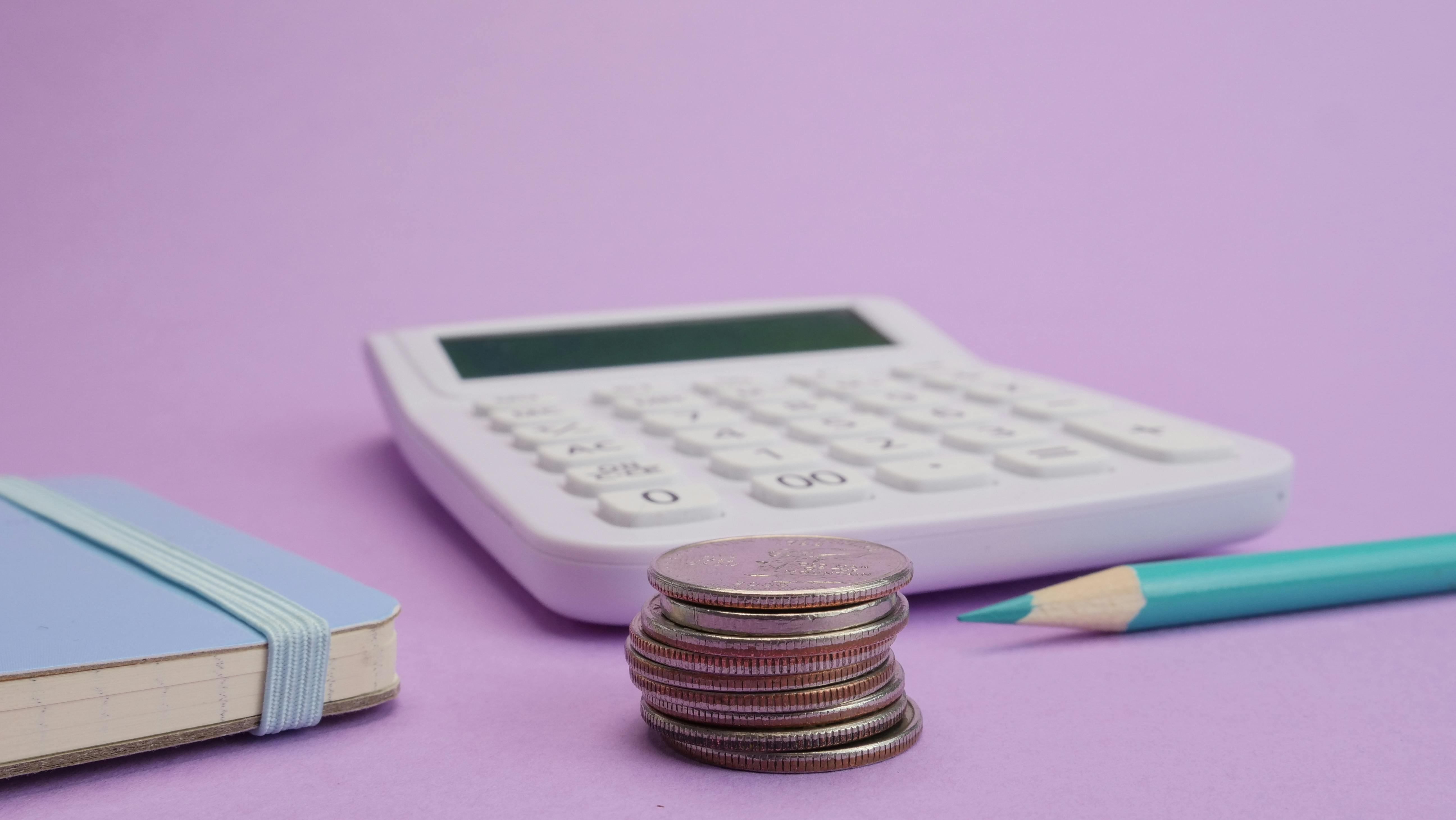 Student budget template setup: calculator, pound coins and planner next to a laptop