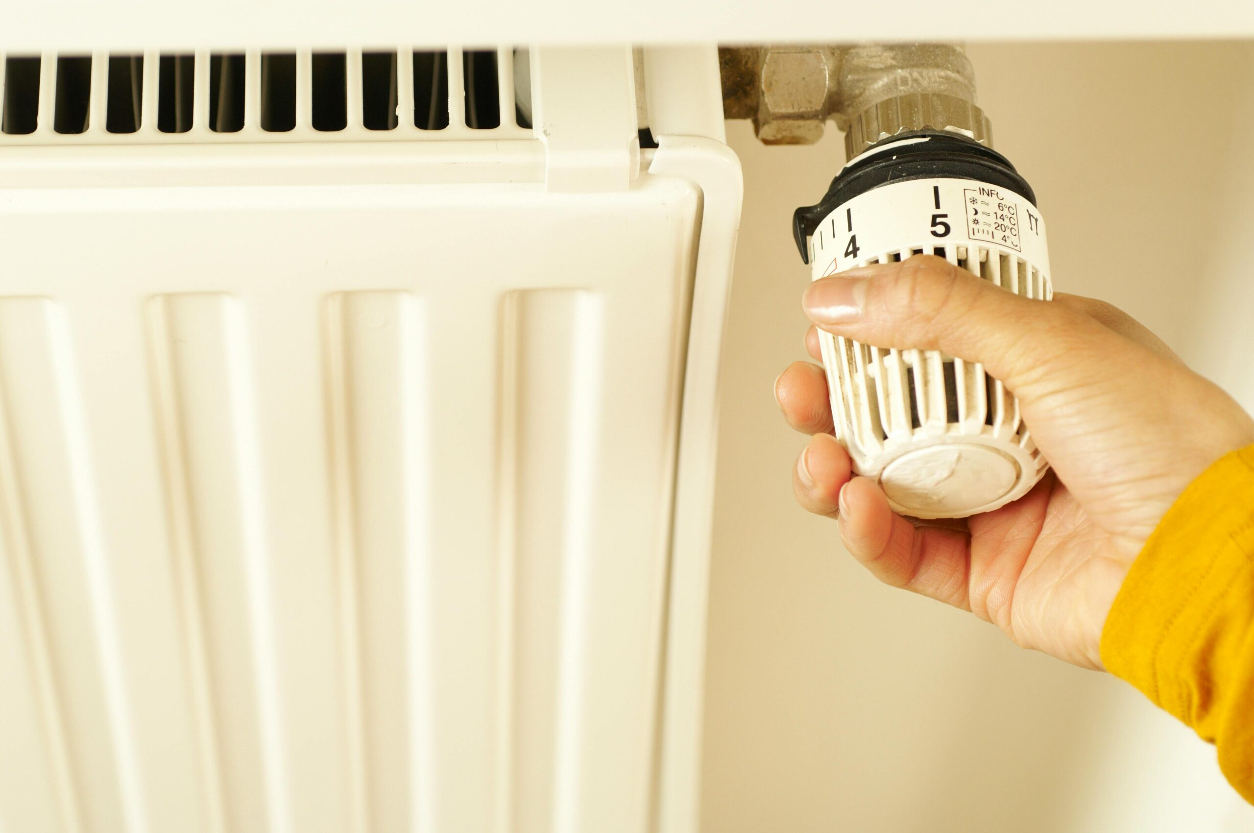 Person adjusting a thermostatic radiator valve in a student bedroom