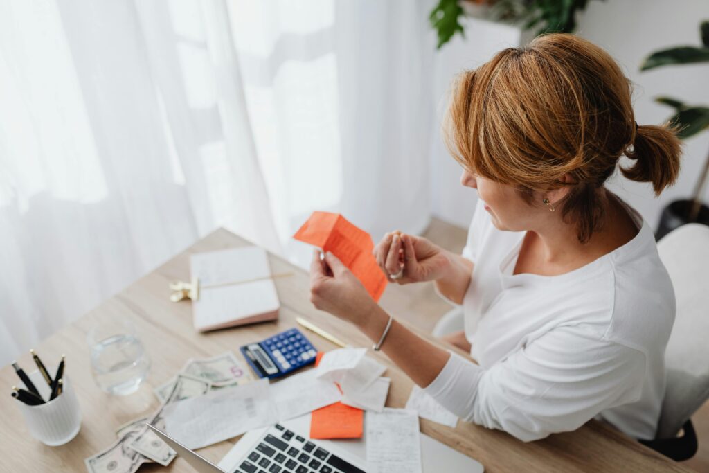 Young woman sorting a pile of receipts with a calculator, working out what needs paying
