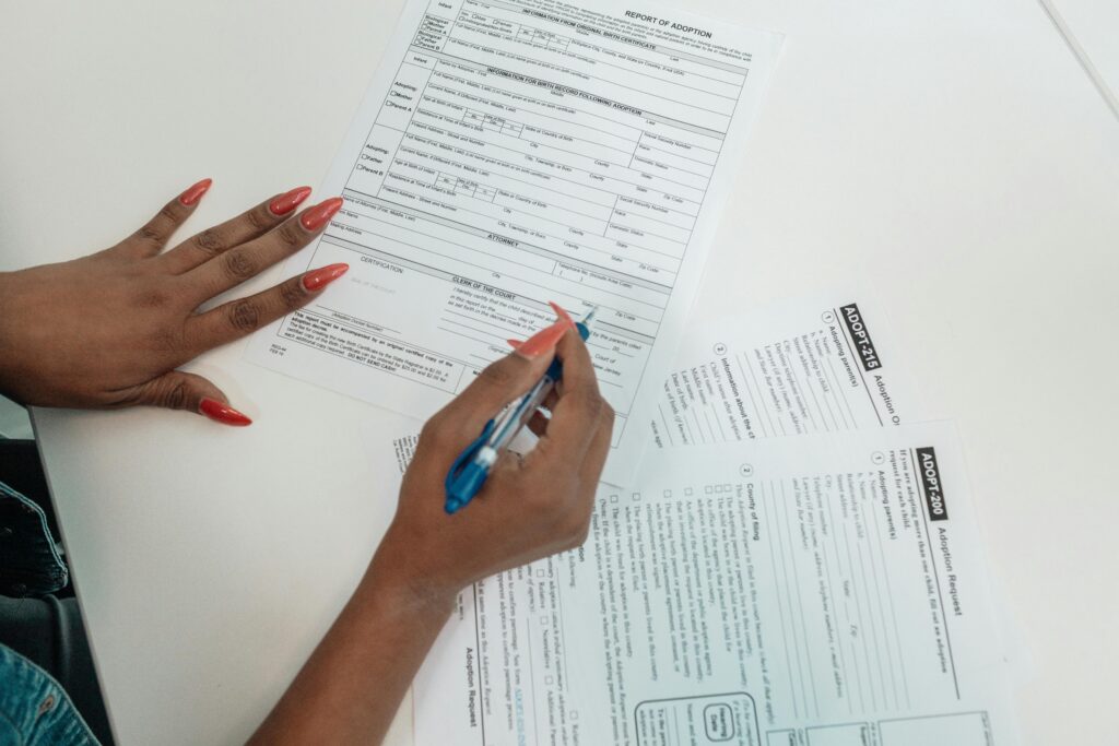 Hands filling in official application forms with a pen