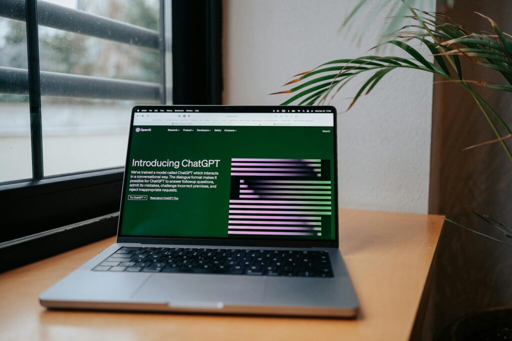 Open laptop by a window showing the OpenAI ChatGPT introduction page, the AI tool many students now use for essays