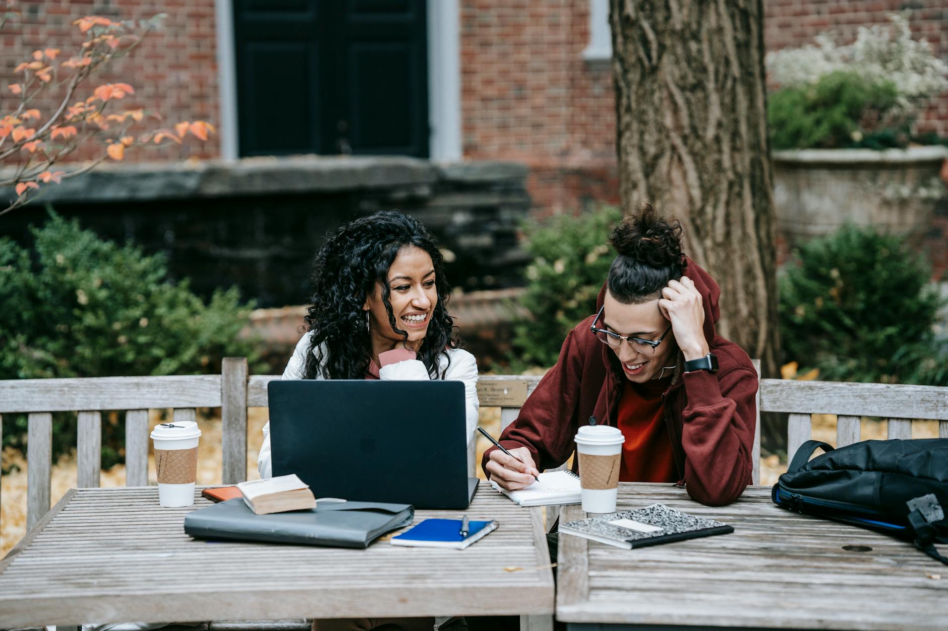 A pair of students reviewing finances on a laptop with notepads beside them