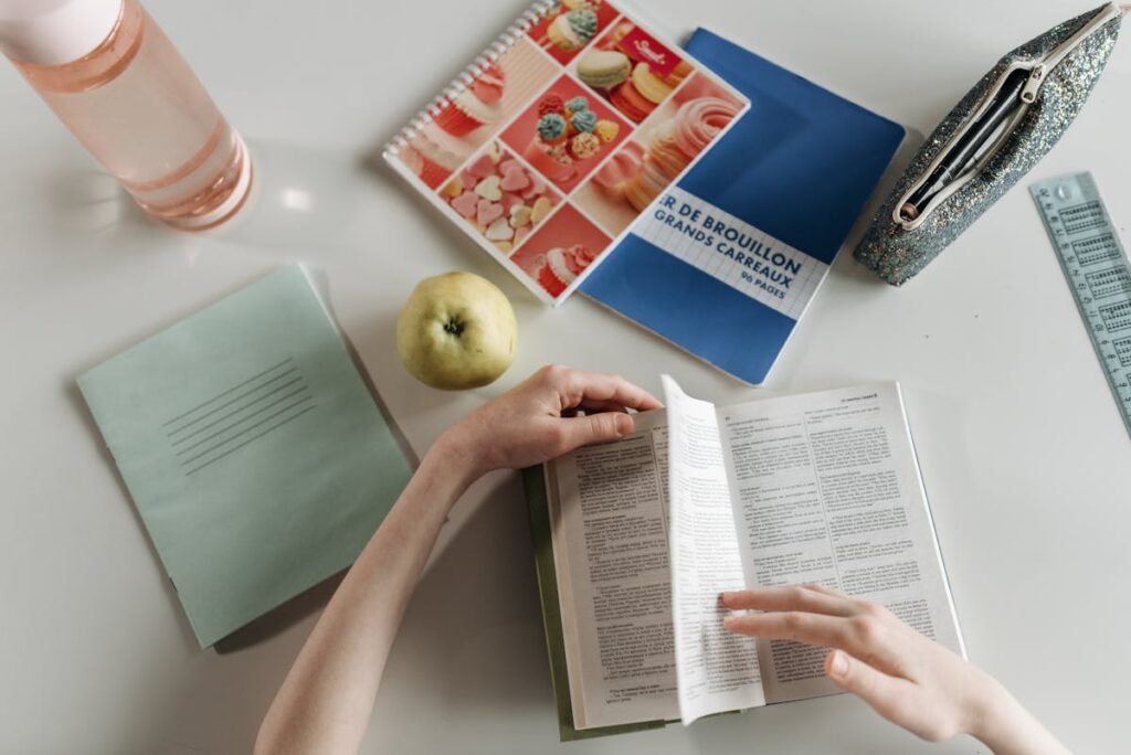 Student studying at desk with revision snacks and textbooks