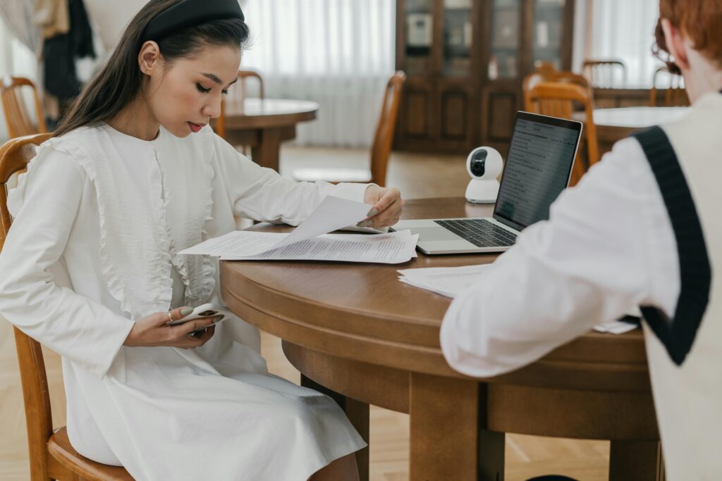 Two UK university students reviewing financial documents and payslips on a shared workspace