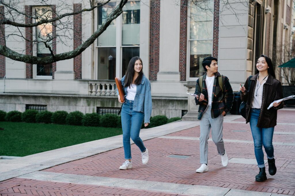 A group of students walking on a university campus sidewalk on a bright day