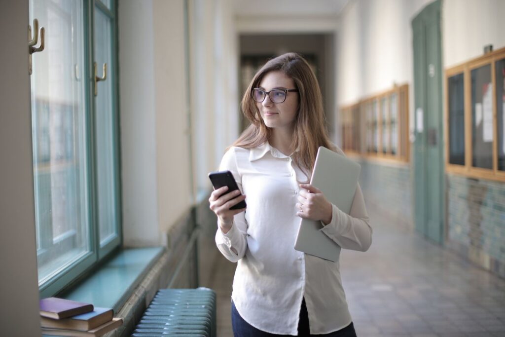 Student in a university corridor checking her application status on a phone