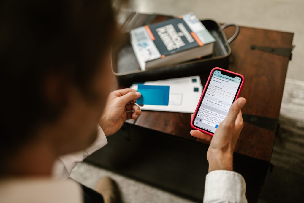 Student holding a bank card and checking their account balance on a phone