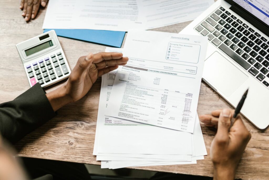 Reviewing a bank statement with a calculator and laptop for a student loan overseas income assessment