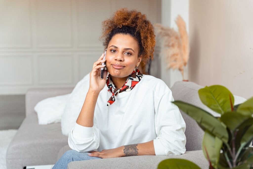 A young woman sitting at home making a phone call, calm and composed