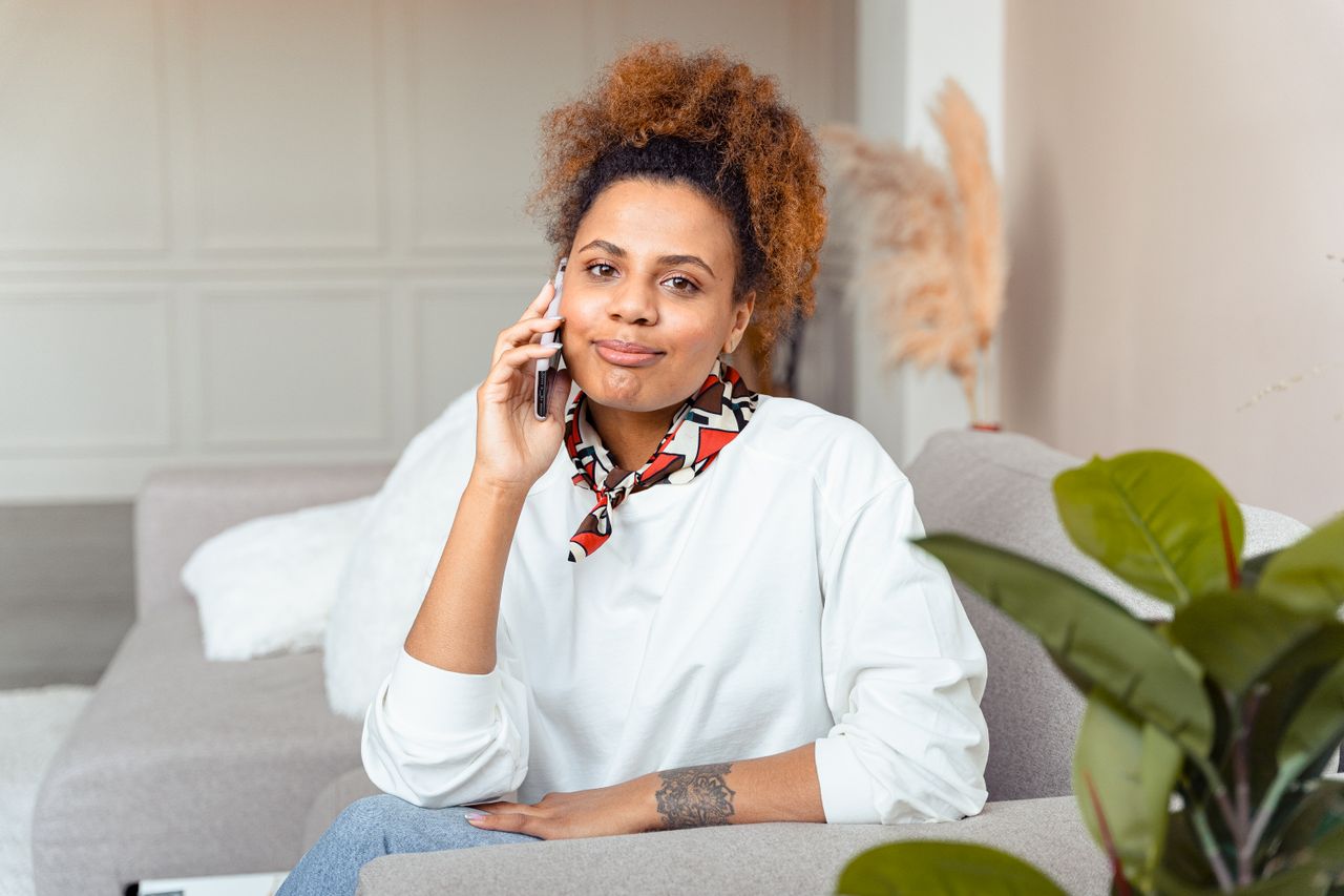 A young woman sitting at home making a phone call, calm and composed