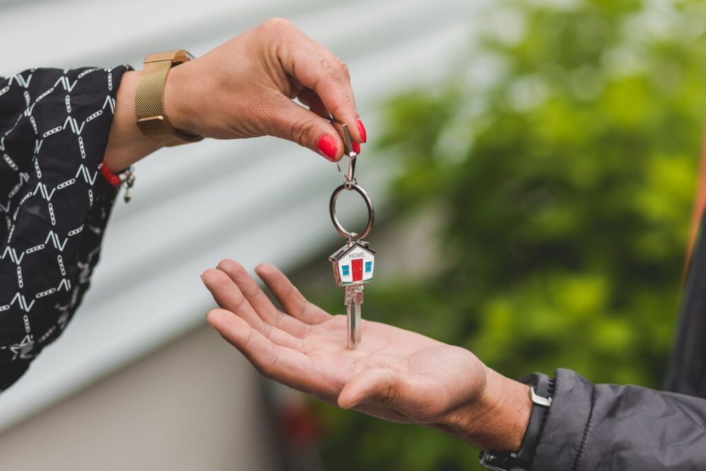 Close-up of a hand passing a door key with a house shaped keychain into another open hand