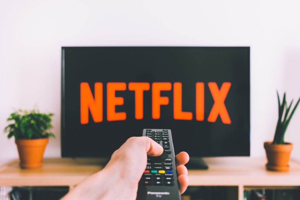 Person pointing a remote at a TV loading Netflix, a typical media subscription