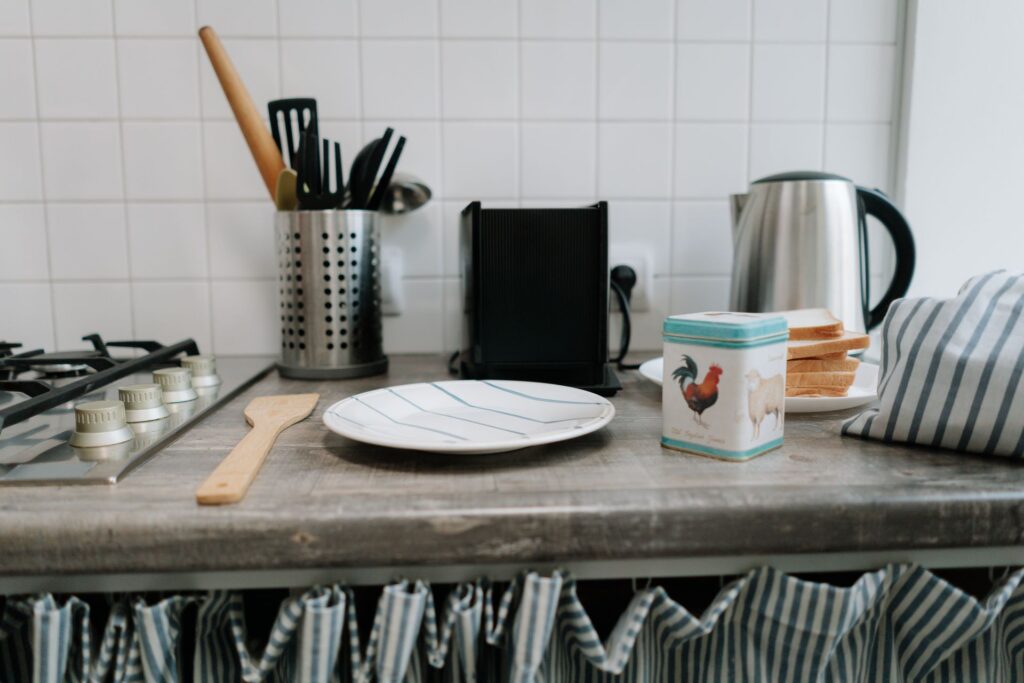 Kettle, toaster, plates and utensils on a kitchen counter, the basic kitchen equipment to bring to uni