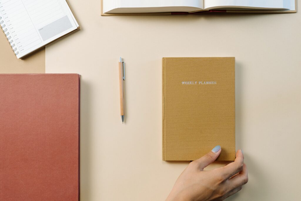 Hand reaching for a weekly planner notebook on a tidy desk
