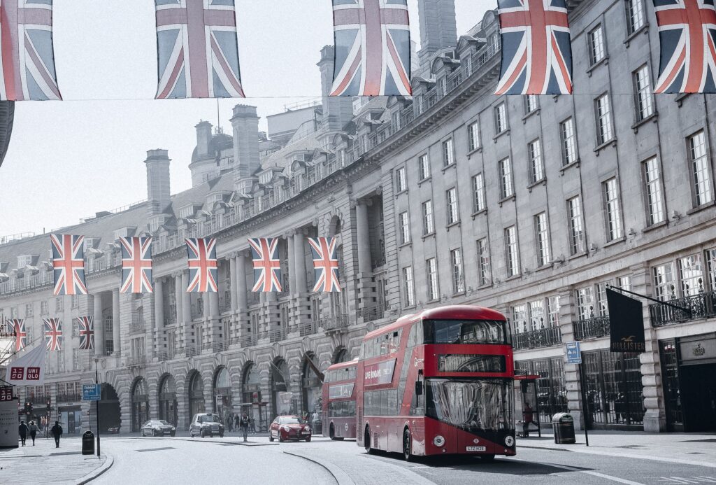 Red double decker bus on Regent Street in London with Union Jack flags overhead