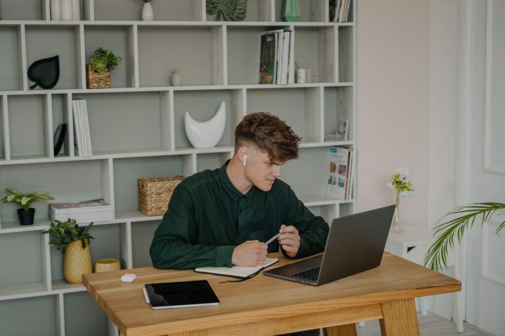 A student sorting out a maintenance loan application at a desk with a laptop and notebook