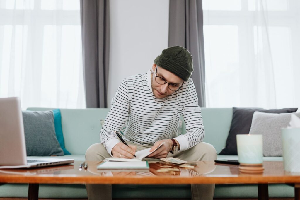 A young person planning a student budget with a notebook and laptop