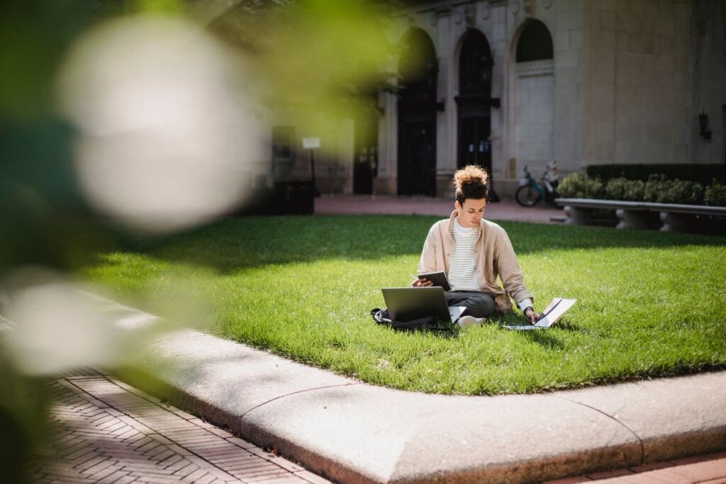 A university student on campus checking a bursary and student finance page on a laptop