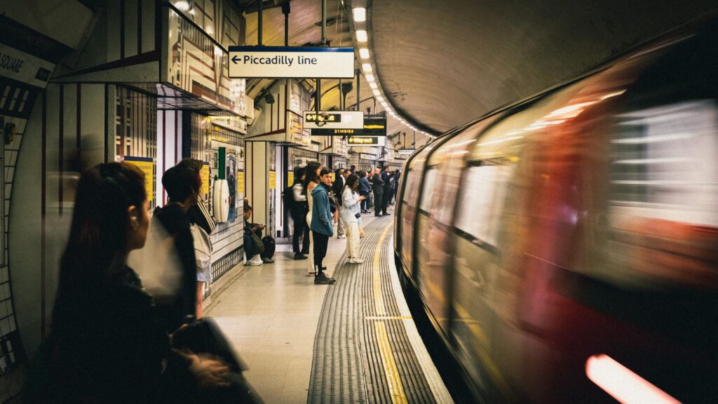 Commuters on a Piccadilly line platform as a train arrives