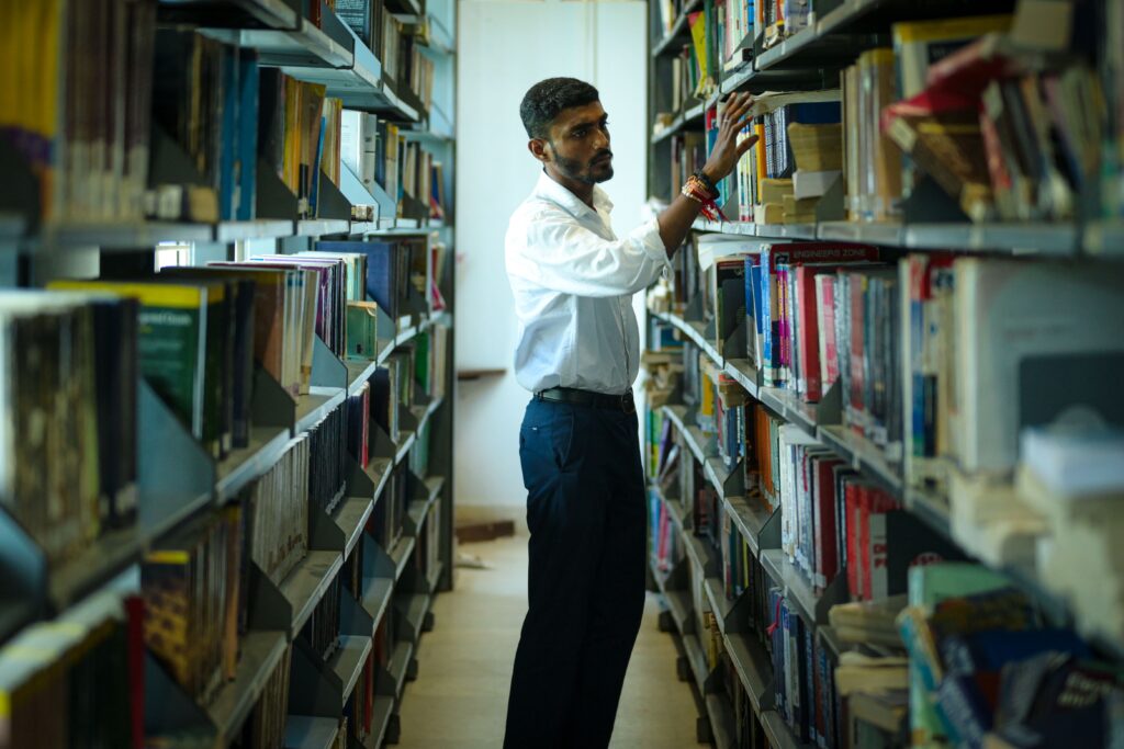 Student browsing bookshelves in a university library aisle