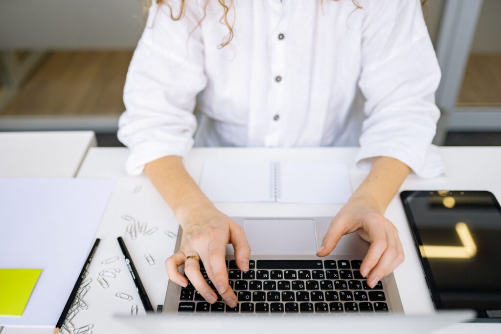 Young woman typing a cover letter on a laptop at a tidy desk