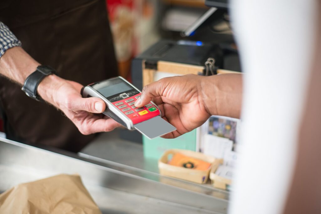Customer paying by credit card on a terminal at a shop counter