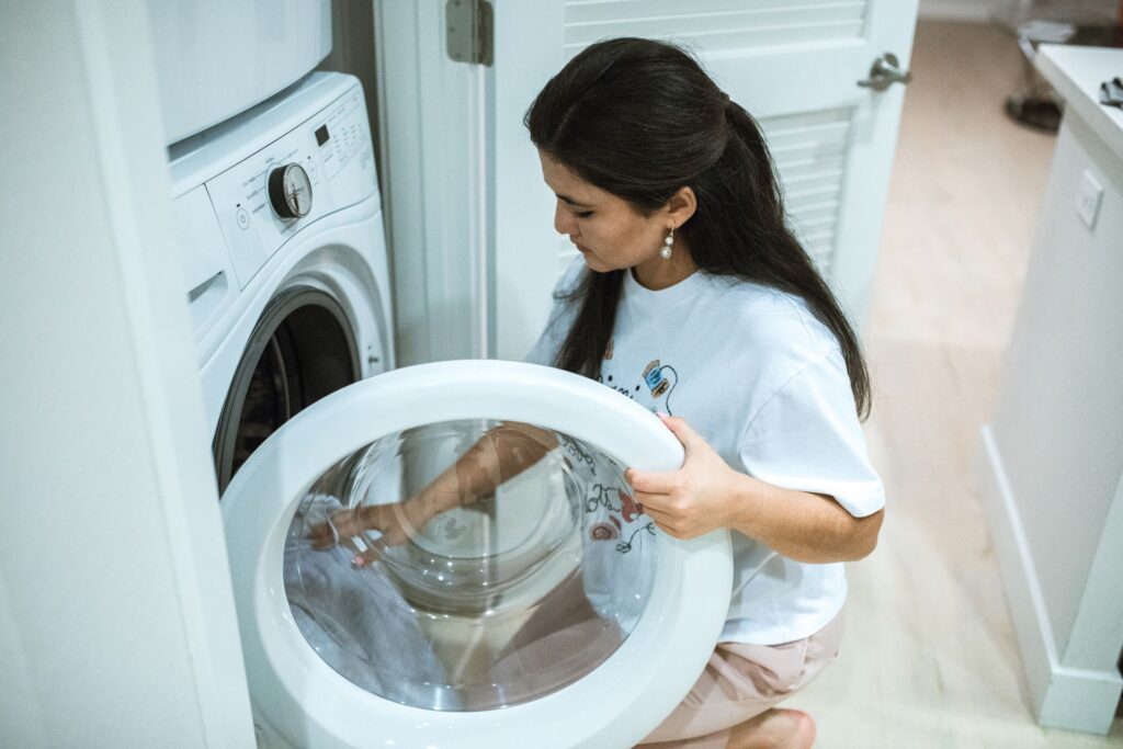 Person loading clothes into a front-loading washing machine at home