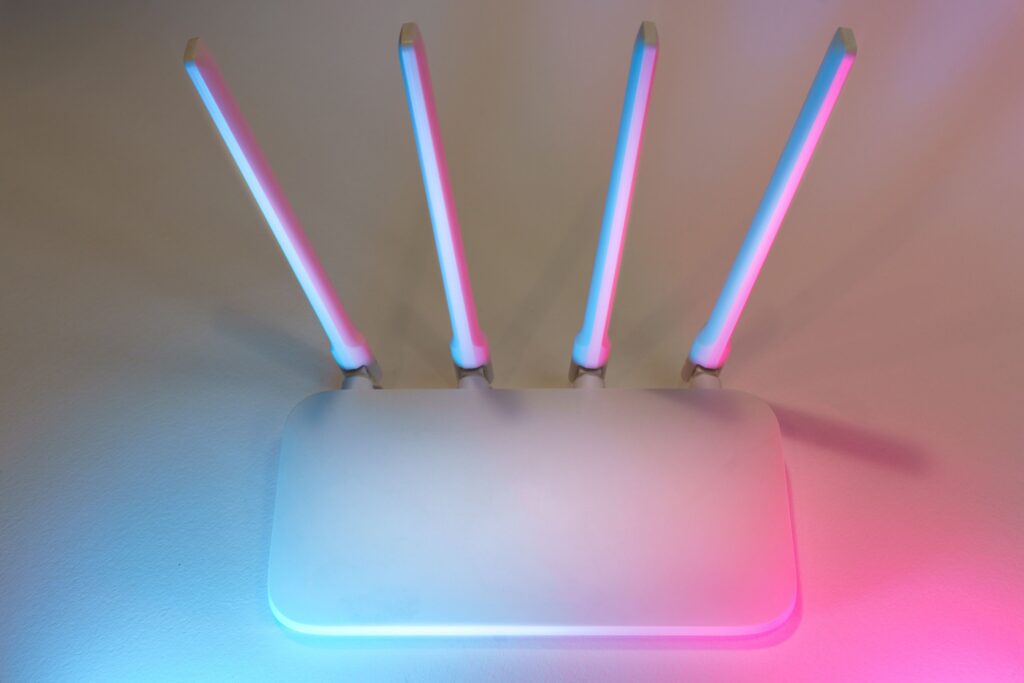 White wireless broadband router with four antennas lit by pink and blue light