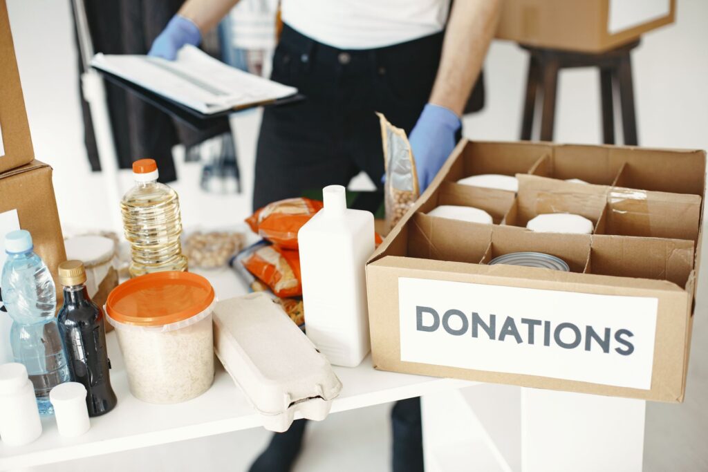Volunteer with a clipboard packing tinned and dry food into a labelled donations box