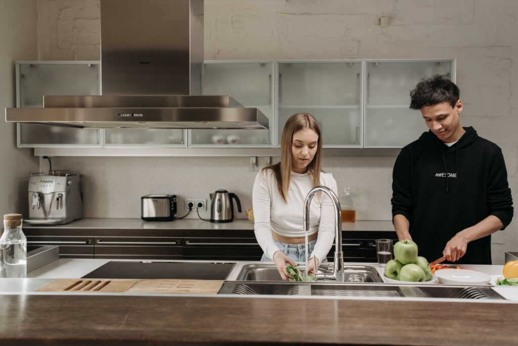 Two young people preparing fresh vegetables together in a shared kitchen