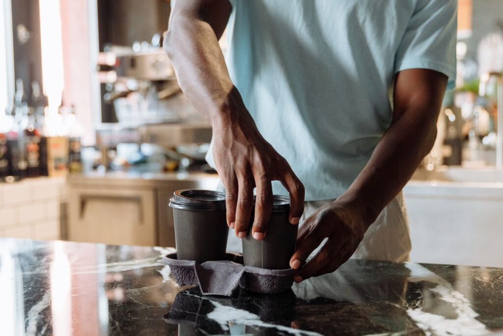 Barista putting takeaway coffee cups into a carrier on a cafe counter
