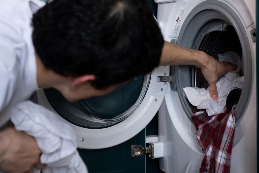 Man loading white laundry into a washing machine