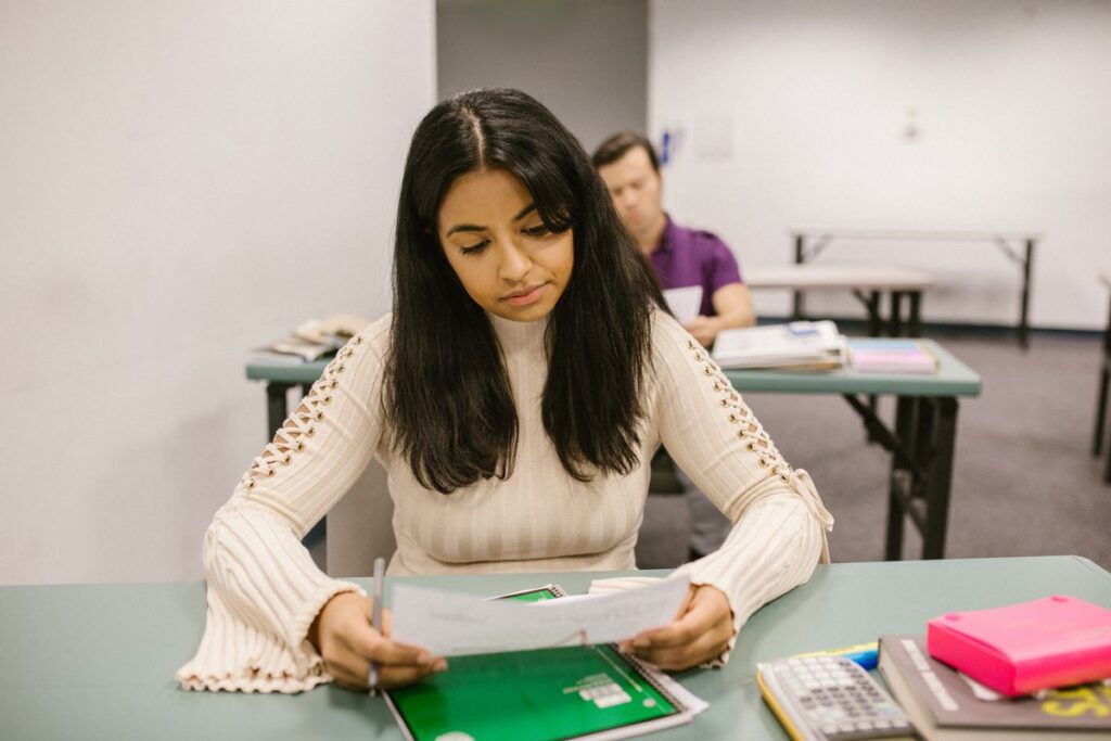 A student reading her exam results paper at a desk in a results-day room