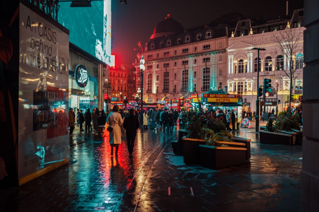 Piccadilly Circus in London at night with crowds, neon lights and wet pavement