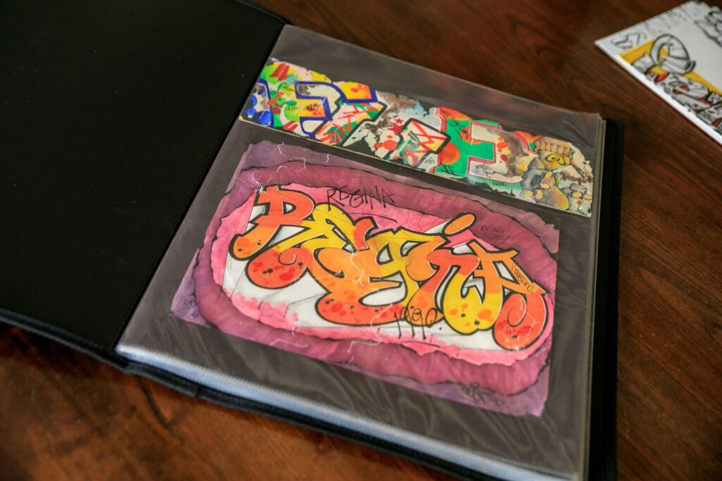 Colourful artwork stored in plastic sleeves inside a black art portfolio folder