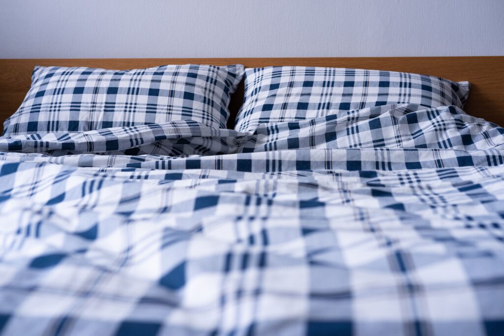 A neatly made single bed with a duvet in a student room