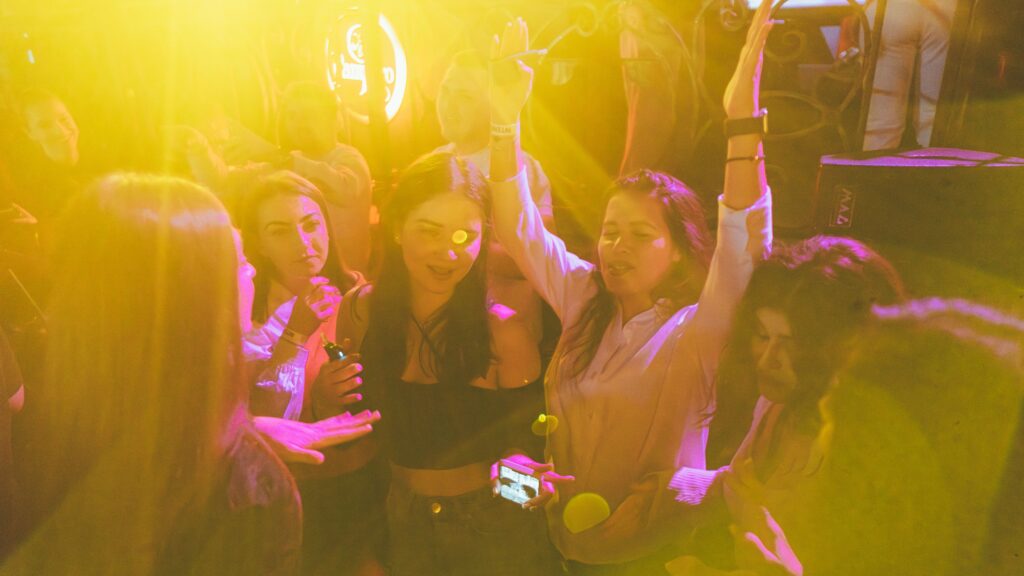 Friends staying close together as they dance at a club night