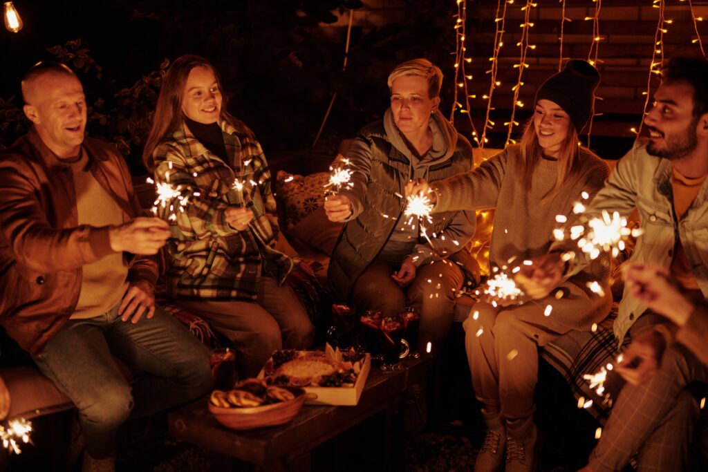 Friends sitting together at an evening gathering holding sparklers