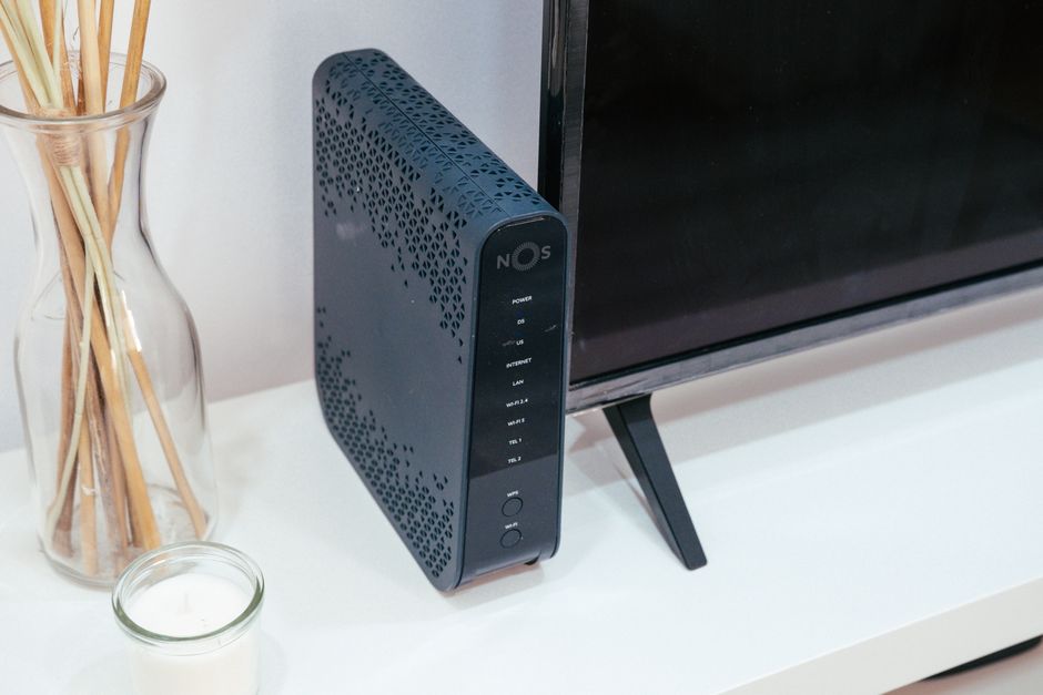 A home broadband router standing beside a television in a shared house