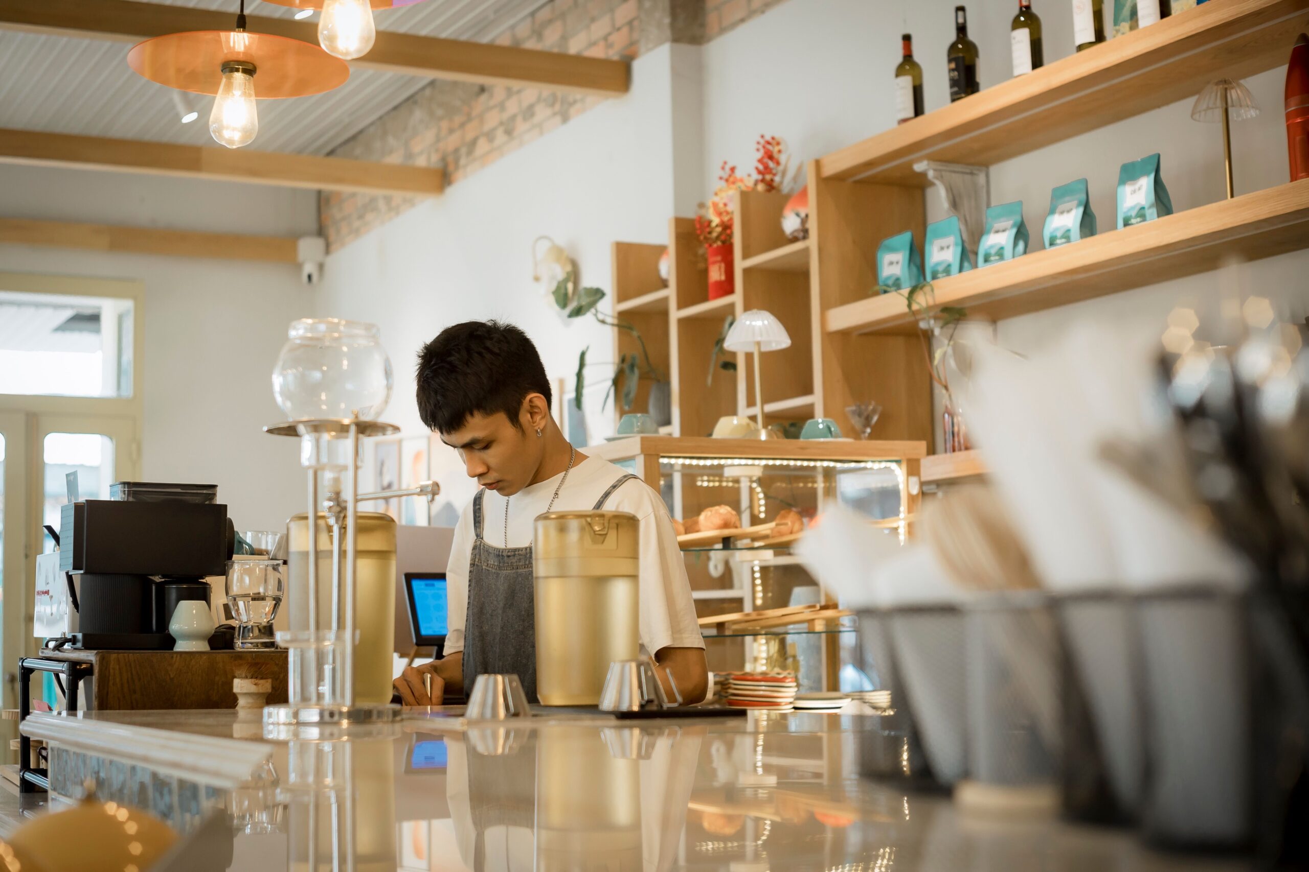 Young barista making coffee behind a cafe counter